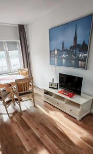 ein Wohnzimmer mit einem Tisch und einem Großbild-TV in der Unterkunft Ankerplatz Lichtblick in Travemünde