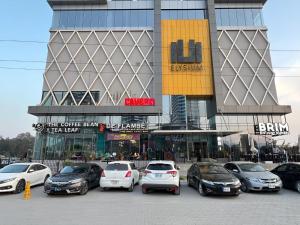 een parkeerplaats met auto's geparkeerd voor een gebouw bij Executive Prestige Hotel Apartments Facing Centautus - Elysium Tower Islamabad in Islamabad