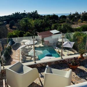 a balcony with chairs and a swimming pool at Palm View Guesthouse, adults only in Luz