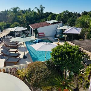 an overhead view of a swimming pool with umbrellas and chairs at Palm View Guesthouse, adults only in Luz