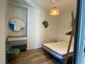 een slaapkamer met een bed, een spiegel en een stoel bij residence fleurie rdc in Saint-Malo