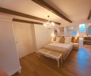 a bedroom with a large bed and a chandelier at La Maison d'Edouard Spa Chauffé Privé prés du Lac in Lanobre