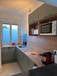 a kitchen with a counter with a microwave and a sink at Appartement cosy, à deux pas de la mer in Ouistreham