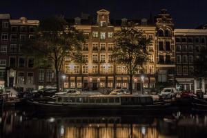 un barco en el agua frente a un edificio en Hotel Estheréa, en Ámsterdam