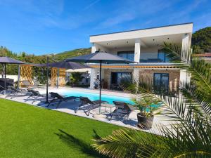 a house with a swimming pool and umbrellas at Villa Milamar in Banjol