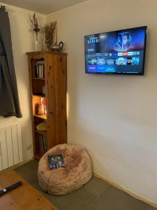a room with a tv on the wall and a dog bed at Studio chaleureux 25m2 100m du centre 3-4 personnes in Vars