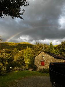 a rainbow in the sky over a stone house at Il Seccatoio in Riolunato