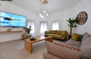 a living room with a couch and a tv at אחוזת סנטוריני - וילה מהממת עם בריכה מחוממת וג'קוזי בעין יעקב in ‘Ein Ya‘aqov