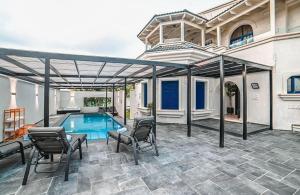 a patio with a pool and chairs and a house at אחוזת סנטוריני - וילה מהממת עם בריכה מחוממת וג'קוזי בעין יעקב in ‘Ein Ya‘aqov