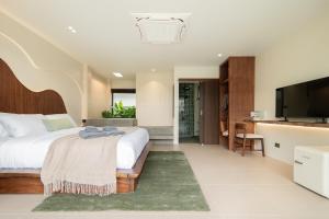 a bedroom with a large bed and a flat screen tv at naravi gardenandpool kohlarn in Ko Sak