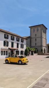 ein gelbes Auto, das auf einem Parkplatz vor einem Gebäude geparkt ist in der Unterkunft Lau Haizeak Meublé 3 étoiles Ascain in Ascain