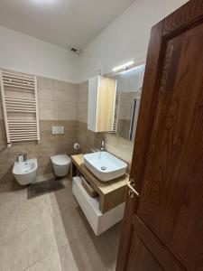 a bathroom with a sink and a toilet and a door at Dimora Sant'Anna Family Suite in Bernalda