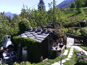 un jardin avec une petite maison avec une haie dans l'établissement Casa Mimosa 1, à Gressan