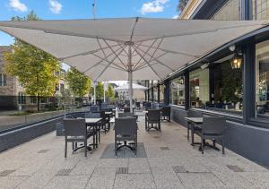 a patio with tables and chairs and an umbrella at Atlas Hotel in Valkenburg +61 photos