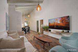 a living room with a large flat screen tv on the wall at הילת השחר - וילה מדהימה עם 3 חדרי שינה ובריכה פרטית בעין יעקב in Mashabbe Sade