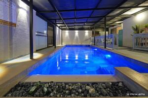 a swimming pool with blue water in a building at הילת השחר - וילה מדהימה עם 3 חדרי שינה ובריכה פרטית בעין יעקב in Mashabbe Sade