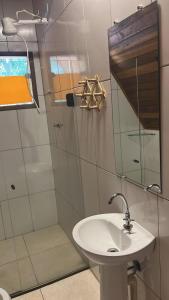 a bathroom with a sink and a shower with a mirror at Chalés Dinhá-Pousada Recanto do Rapa in Brumadinho