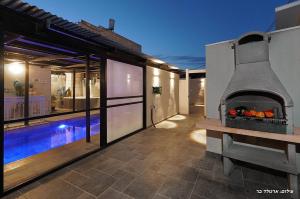 a backyard with an outdoor oven next to a house at הילת השחר - וילה מדהימה עם 3 חדרי שינה ובריכה פרטית בעין יעקב in Mashabbe Sade