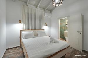 a bedroom with a bed with white sheets and a window at הילת השחר - וילה מדהימה עם 3 חדרי שינה ובריכה פרטית בעין יעקב in Mashabbe Sade +30 photos