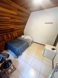 a small room with a bed and a chair at Chalés Dinhá-Pousada Recanto do Rapa in Brumadinho