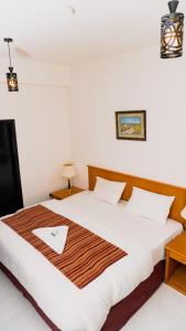 een slaapkamer met een groot bed met een houten hoofdeinde bij PAN Hotel Apartments in Sharjah