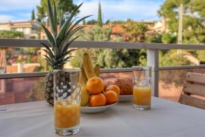 Una mesa con un bol de fruta y dos vasos de zumo de naranja. en Escapade à Bandol balcon verdoyant et plage à deux pas, en Bandol 17 fotos más