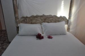 a bed with white pillows and purple flowers on it at Bulu Apartments in Kilifi
