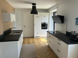 eine Küche mit weißen Schränken und einer schwarzen Arbeitsplatte in der Unterkunft Corps de ferme alsacien in Grassendorf