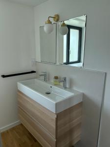 ein Badezimmer mit einem weißen Waschbecken und einem Spiegel in der Unterkunft Corps de ferme alsacien in Grassendorf + 46 Fotos