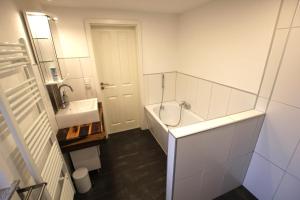 a bathroom with a sink and a tub and a toilet at Ferienhaus Weideblick in Hymendorf +17 photos