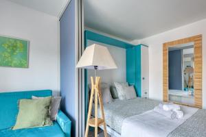 Un dormitorio con una cama azul y un espejo. en Escapade à Bandol balcon verdoyant et plage à deux pas, en Bandol