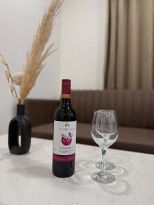 eine Flasche Wein und ein Glas Wein auf dem Tisch in der Unterkunft Cozy Studio with Private Terrace & Golf Course View Road in Gurgaon