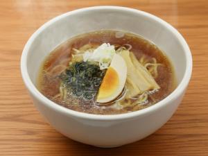 a bowl of soup with an egg on a table at Dormy Inn Hirosaki in Hirosaki