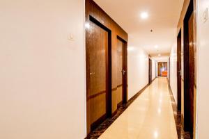 a hallway with wooden doors and white walls at Collection O by OYO Flavour in Āsansol