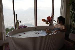 a young child sitting in a bath tub in front of a window at Cabaña en Santa Elena con vista a Medellín in Santa Elena +58 photos