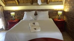 a bedroom with a white bed with two night stands at Big Tuskers Bush Camp in Marloth Park