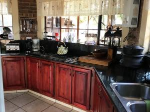 a kitchen with red wooden cabinets and a sink at Big Tuskers Bush Camp in Marloth Park
