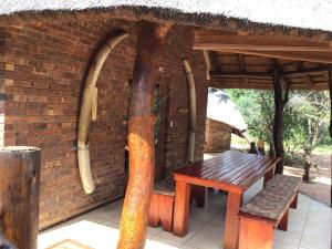 a brick building with a wooden bench and a brick wall at Big Tuskers Bush Camp in Marloth Park +7 photos