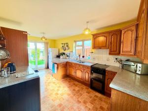 una cocina con armarios de madera y electrodomésticos negros en A Perfect Work Base & Family House in Fishpoads, en Bristol
