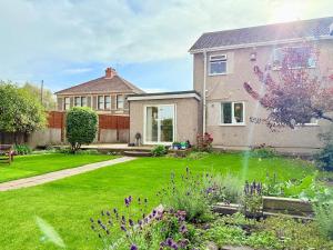 una casa con un patio verde con flores púrpuras en A Perfect Work Base & Family House in Fishpoads, en Bristol