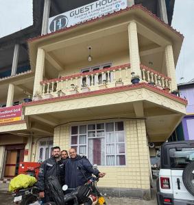 a group of three men standing in front of a building at JD House in Tawang