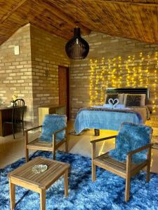 ein Schlafzimmer mit einem Bett und zwei Stühlen und einem Tisch in der Unterkunft Quiosque Família Chalé Beija-Flor in Joanópolis