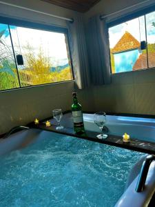 eine Badewanne mit zwei Gläsern und eine Flasche Wein in der Unterkunft Quiosque Família Chalé Beija-Flor in Joanópolis