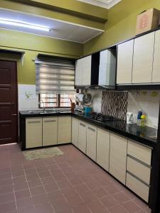 a kitchen with white cabinets and black counter tops at Kota Puteri Vibe Kampung Homestay in Batu Arang
