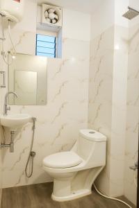 a white bathroom with a toilet and a sink at Vinayaka in Patna
