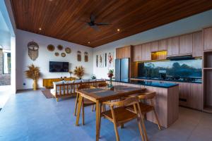a kitchen with wooden cabinets and a table and chairs at KAPI Sebatu Villa in Tampaksiring