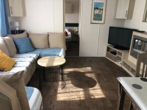 a living room with a couch and a television at Mobilhome spacieux et calme in Pont-Aven