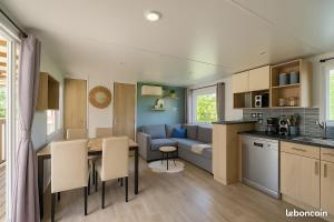 a kitchen and living room with a table and a couch at Charmant Mobilhome entre Lac&Océan et proche de la Vélodyssée in Sainte-Eulalie-en-Born