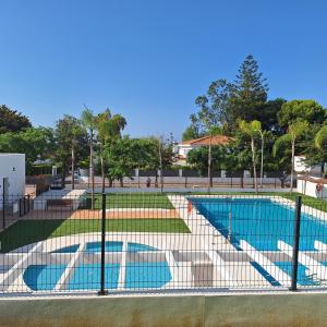 a fence around a tennis court with a pool at Chilches Sunset Beach in Vélez-Málaga