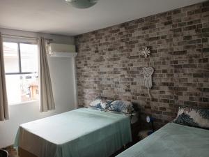 サン・ビセンテにあるApartamento Horizonte Azulのレンガの壁、ベッド2台が備わるベッドルーム1室が備わります。